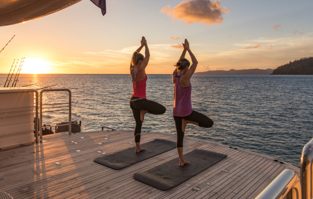 Persons doing Pilates on a yacht at sunset