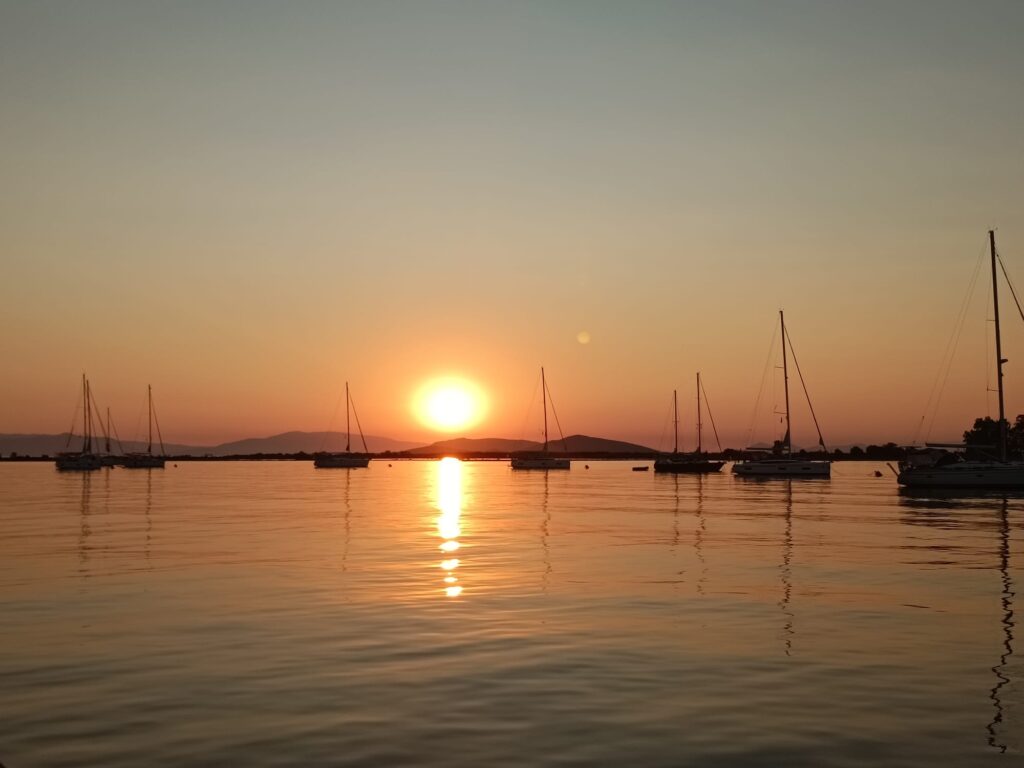 A fleet of catamarans anchored in a calm Mediterranean bay during a golden sunset, illustrating a silent digital detox retreat.