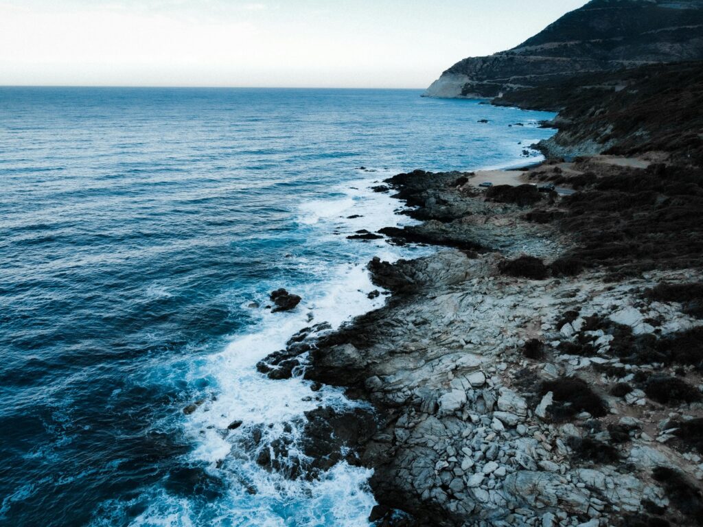 Dramatic aerial view of the rugged granite cliffs and deep blue Mediterranean waters along the northwest coast of Corsica.
