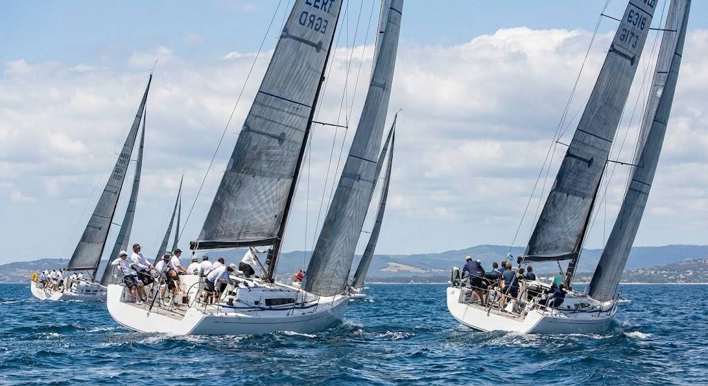 Racing sailboats sailing close-hauled during a regatta training session, demonstrating proper sail trim and crew coordination on blue water.
