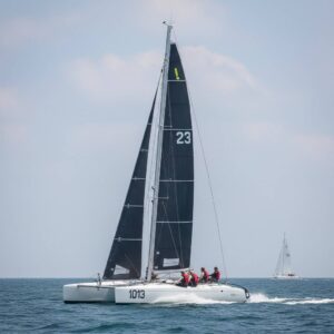 A racing catamaran with a professional crew executing a high-speed maneuver during a regatta training session.